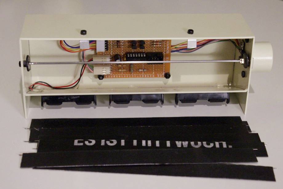 Die Fallblattanzeige, auseinandergebaut: Die Blätter liegen davor. Man sieht die Lochrasterplatine mit der Elektronik innen an der Rückseite montiert (normalerweise hinter den Blättern versteckt).